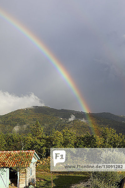 Landschaftliche Ansicht des Regenbogens über den Bergen vor bewölktem Himmel