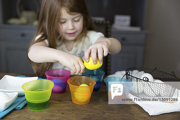 Mädchen färbt Ostereier auf dem heimischen Tisch