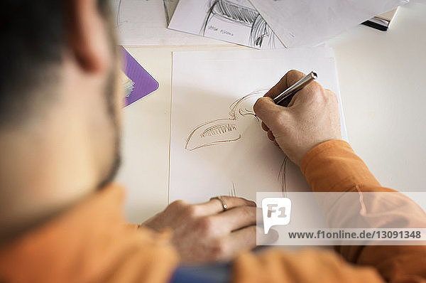 Hochwinkelansicht eines Handwerkers  der in einer Werkstatt einen Entwurf auf Papier herstellt
