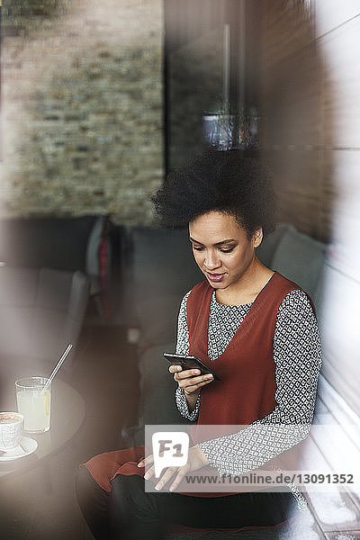 Geschäftsfrau benutzt Smartphone  während sie im Café auf dem Sofa sitzt