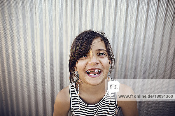 Portrait of happy girl standing against shutter