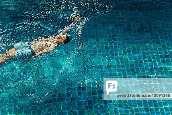 Hochwinkelansicht eines Mannes  der im Schwimmbad eines Touristenortes schwimmt