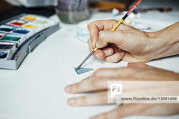Geschnittene Hände einer Künstlerin beim Malen im Atelier