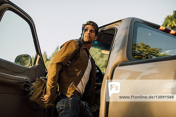 Man looking away while entering into pick-up truck