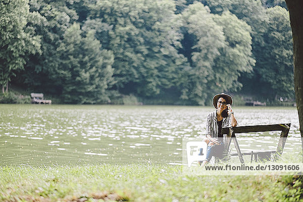 Bildnis einer Frau  die auf einer Bank am Seeufer im Wald sitzt