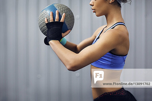 Mittelteil einer Sportlerin  die mit Medizinball im Fitnessstudio trainiert