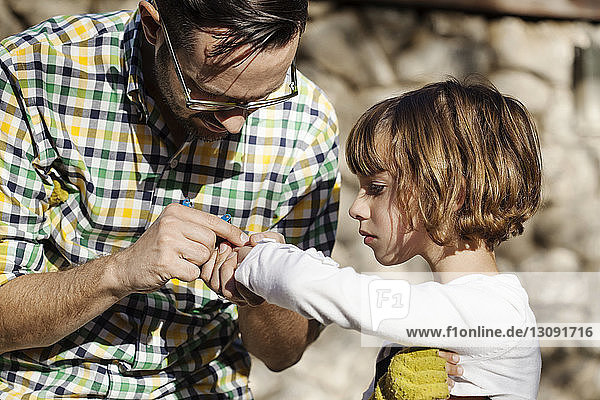 Close-up of father checking hand of daughter