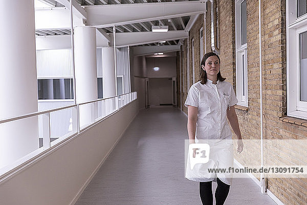 Zuversichtliche Ärztin  die beim Gehen im Krankenhauskorridor wegschaut
