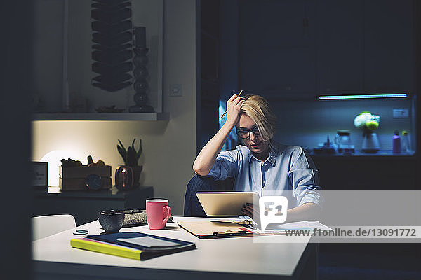 Geschäftsfrau mit dem Kopf in der Hand am Tablet-Computer am Schreibtisch im Heimbüro