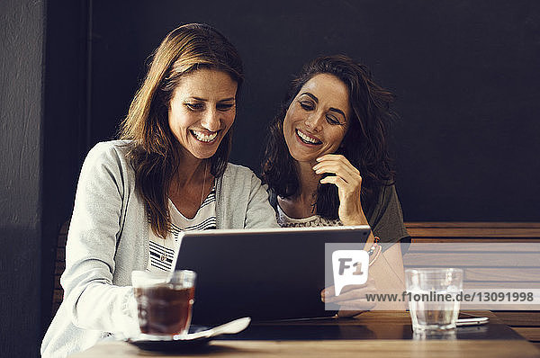 Fröhliche reife Freundinnen benutzen Tablet-Computer im Café