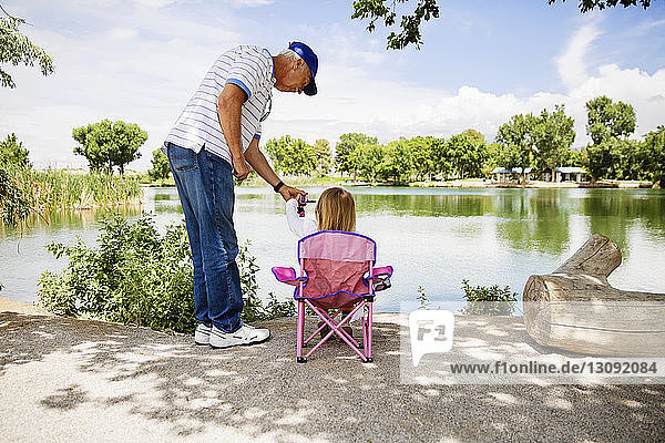 Grandfather and granddaughter fishing at lakeshore