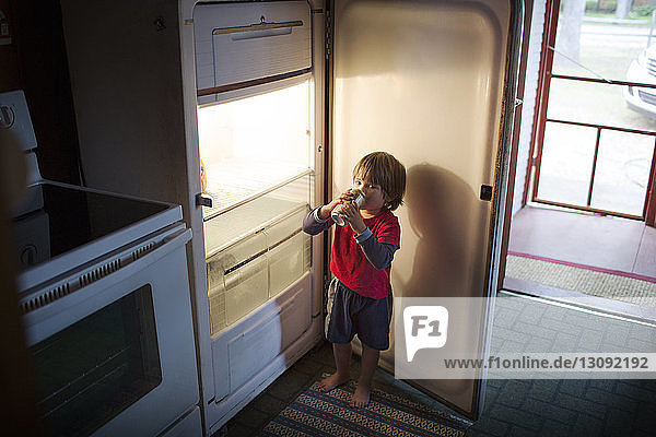 Boy drinking canned drink from fridge