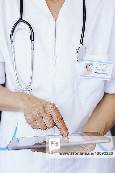 Mittelsektion eines Arztes  der einen Tablet-Computer im Krankenhaus benutzt
