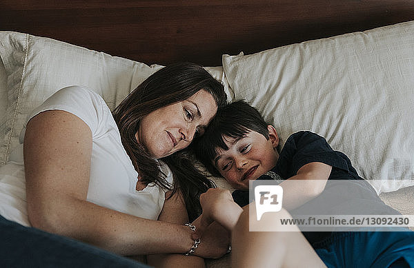 Mother and son lying on bed at home
