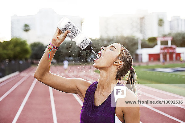Weibliche Athletin trinkt Wasser auf Rennstrecken