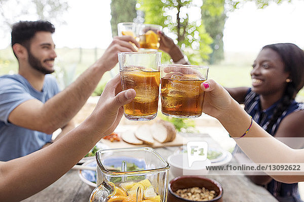 Friends toasting iced tea glasses at outdoor table