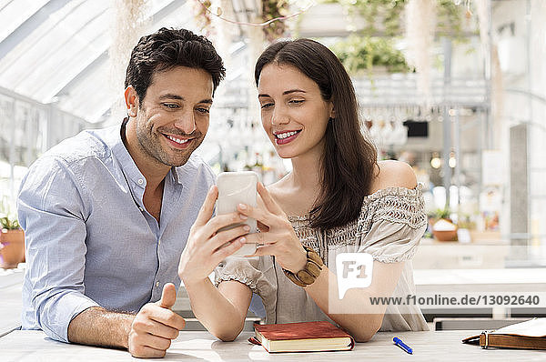 Happy couple using smart phone at sidewalk cafe