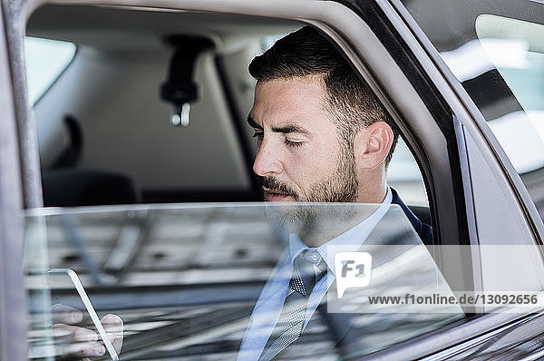 Businessman using smart phone in car