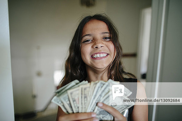 Porträt eines fröhlichen Mädchens mit Papiergeld zu Hause