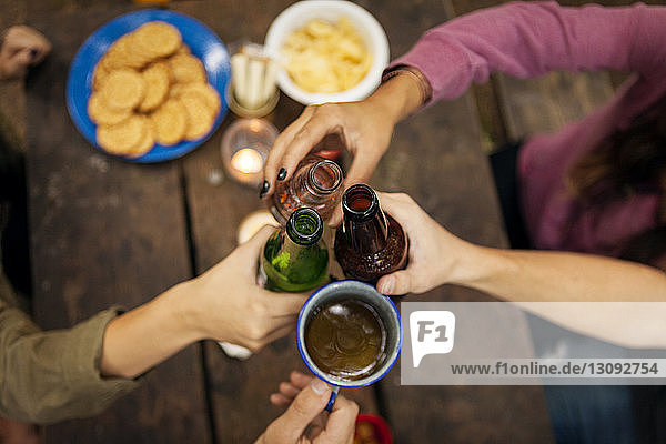 Draufsicht auf Hände  die am Picknicktisch im Wald auf Getränke anstoßen