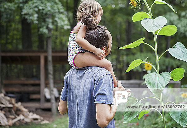 Happy father carrying girl on shoulders in backyard
