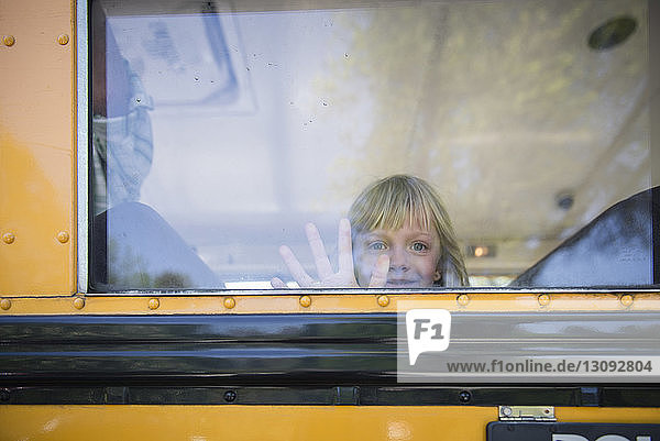 Porträt eines Mädchens  das durch ein Fenster schaut  während es im Schulbus fährt