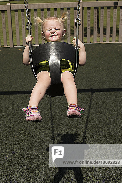 High angle view of cute girl swinging in playground during sunny day