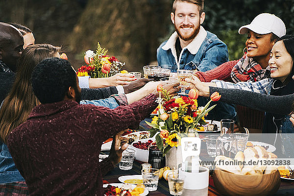 Freunde stoßen Wein an  während sie im Hinterhof am Tisch sitzen