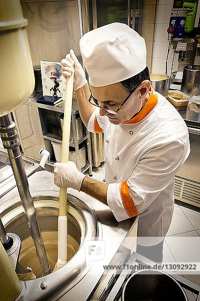Hochwinkelansicht des Küchenchefs beim Teigmischen in der Maschine in der Fabrik