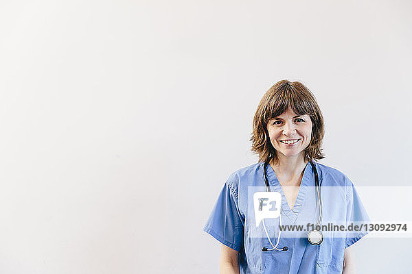 Porträt einer lächelnden Ärztin mit Stethoskop vor weissem Hintergrund stehend