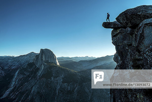 Tiefblick auf einen Mann  der auf einem Berg im Yosemite National Park vor klarem  blauem Himmel steht