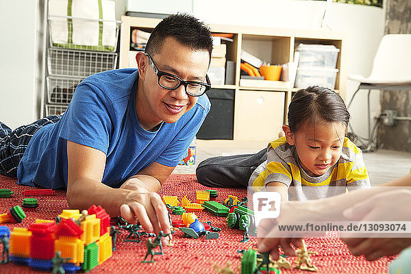 Father and children playing with toys on floor at home