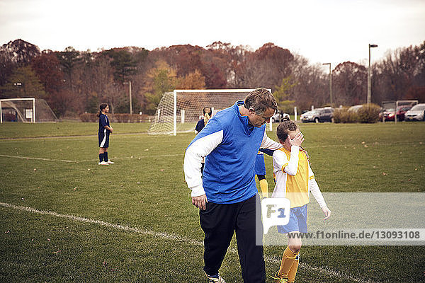 Trainer tröstet Fußballspieler beim Spiel auf dem Spielfeld