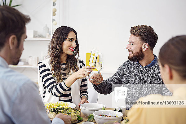 Smiling friends raising celebratory toast at dinning table