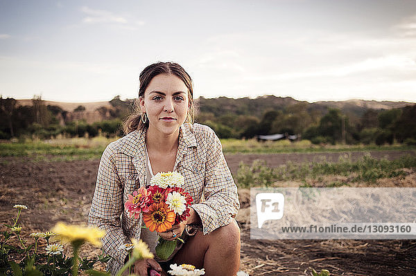Porträt einer selbstbewussten Bäuerin mit schönen Blumen auf dem Feld