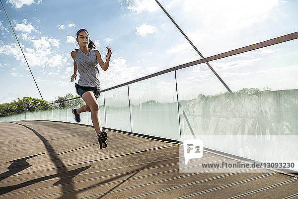 Weibliche Athletin läuft auf Brücke gegen Himmel