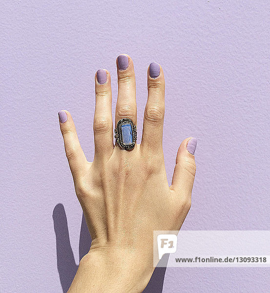 Frauenhand mit Ring gegen violette Wand