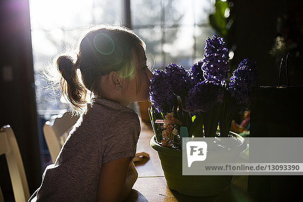 Seitenansicht eines Mädchens  das Blumen auf dem Tisch zu Hause riecht