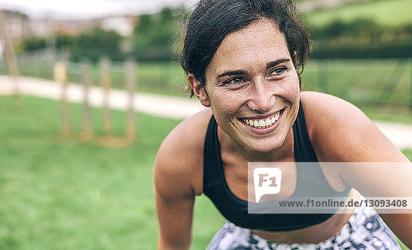 Glückliche Frau beugt sich beim Sport im Park