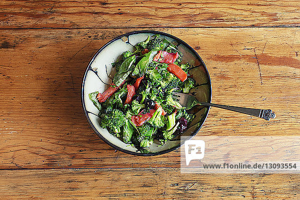 Draufsicht auf Salat in Schüssel serviert mit Gabel auf dem Tisch