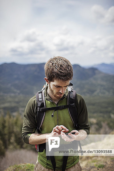 Male hiker using phone on mountain