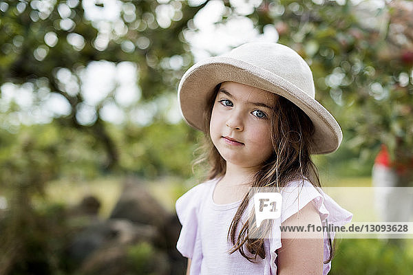 Porträt eines süßen Mädchens mit Hut im Park stehend