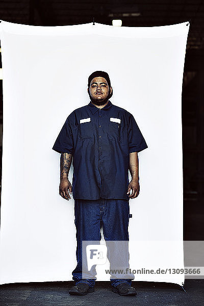 Full length portrait of young worker wearing uniform standing against white backdrop