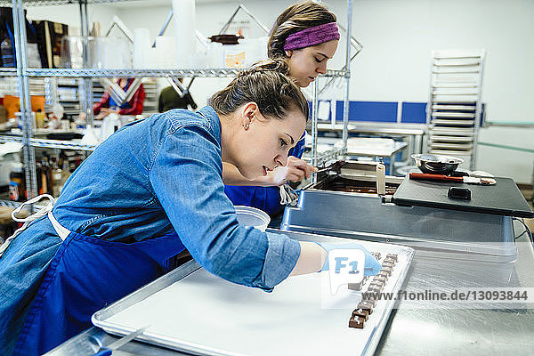 Weibliche Mitarbeiter  die in der Fabrik Schokolade bei Tisch zubereiten