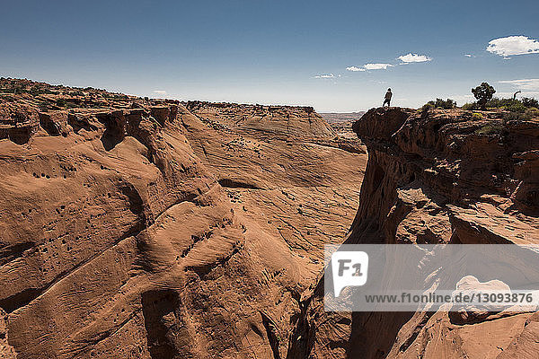 Mid distance view of man standing on cliff at Grand Staircase-Escalante National Monument against sky