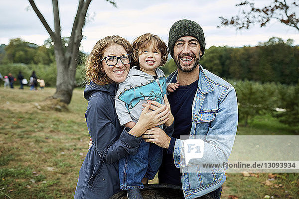 Porträt einer glücklichen Familie auf dem Feld im Obstgarten stehend