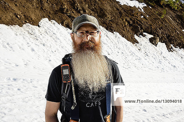 Portrait of confident man standing on snow covered mountain