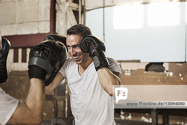 Happy male boxer practicing with senior man in gym