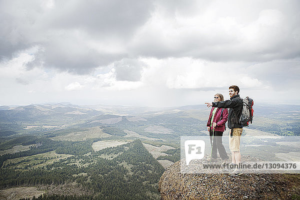 Son pointing away while standing with mother on mountain