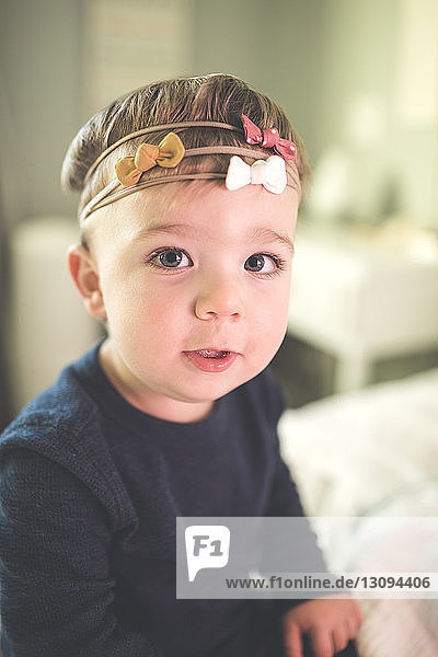 Porträt eines kleinen Jungen mit Stirnband  der zu Hause auf dem Bett sitzt